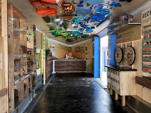 Interior view of the Trash Lab mobile exhibit with colorful materials on the ceiling and interactive displays along the walls.
